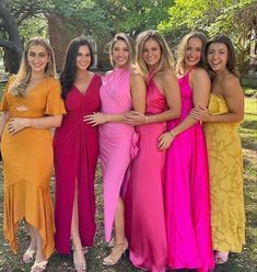 four women in different colored dresses posing for the camera with their arms around each other