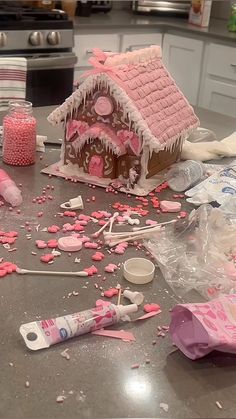 a kitchen counter topped with lots of pink and white candy canes next to a gingerbread house