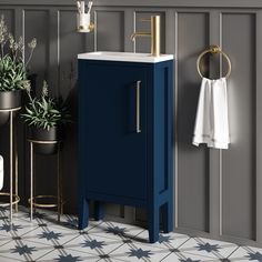 a bathroom with a blue cabinet and white towel hanging on the wall next to potted plants