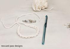 the crochet hook is next to some yarn and a ball of knitting thread