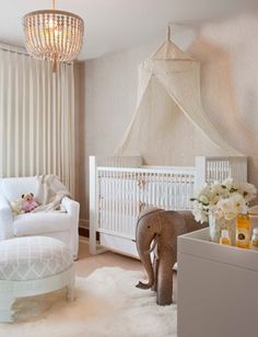 an elephant standing next to a baby crib in a room with white walls and curtains