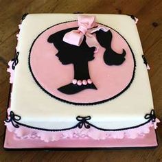 a pink and white cake with a silhouette of a woman