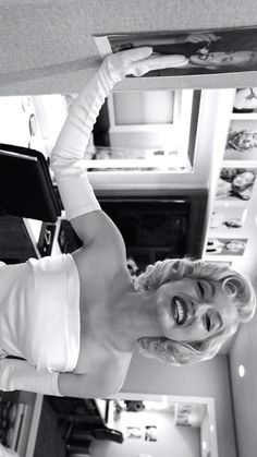 black and white photograph of a woman holding up an object in the air above her head