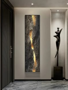 an abstract painting hangs on the wall next to a statue in a room with white walls