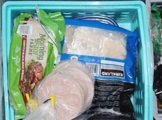 a blue basket filled with lots of food items next to plastic wrappers and bags