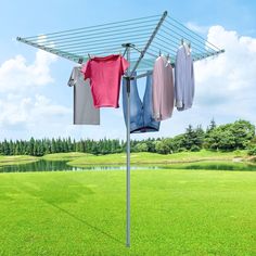 clothes are hung on an ironing board in front of a green field and blue sky