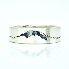 a silver ring with mountains in the middle and blue stones on it's sides