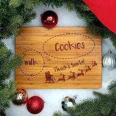 a cutting board with cookies on it surrounded by christmas ornaments