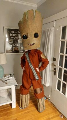 a person in a costume standing on a wooden floor next to a white door and window