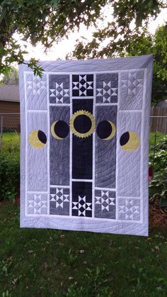 a white quilt hanging from a tree in the yard with an owl design on it