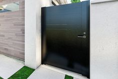 an entrance to a modern home with grass in the front yard