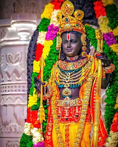 an idol is displayed in front of a flower display at a temple, with flowers all around it