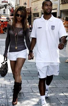 a man and woman are walking down the street holding hands, both wearing white shorts