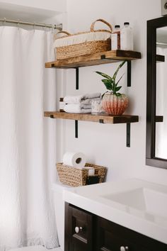 a bathroom with two open shelves above the toilet and a basket on the wall next to it