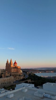 an old church sits on top of a hill next to the ocean at sunset or dawn