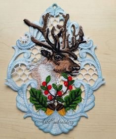 an embroidered deer head with holly berries and pine cones