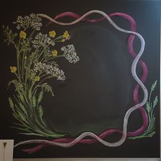 a chalkboard with flowers on it and a ribbon in the middle that is painted