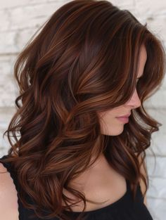 These rich dark auburn waves create a sophisticated and elegant look, perfect for a night out or a formal event. The dark auburn tones add warmth and richness, making the hair look luxurious and full. This style suits all face shapes and is ideal for clients wanting a dramatic change. Picture this look in an upscale beauty salon, where the professional lighting showcases the deep, rich color and the soft waves. Fall Hair Colors Dimensional, Fall Hair Colors Cinnamon, Sun Kissed Cinnamon Hair, Root Beer Hair Color, Mid Length Dark Auburn Hair, Deep Cinnamon Hair Color, All Over Auburn Hair Color, Warm Rich Brunette Hair, Brunette With Red Lowlights