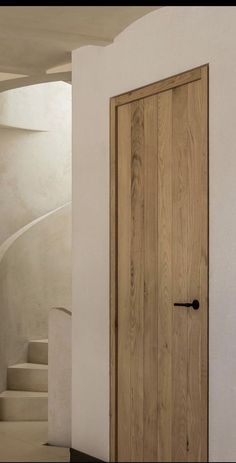 an open wooden door in a white room next to some stairs and a stair case