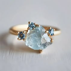 a gold ring with two blue and white stones on it, sitting on top of a table