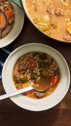 two white bowls filled with soup on top of a wooden table