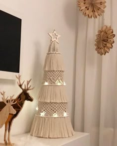 a white christmas tree with lights on it next to a deer figurine and other decorations