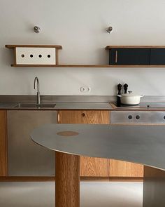 a modern kitchen with stainless steel counter tops and wooden cabinetry, along with shelves above the sink