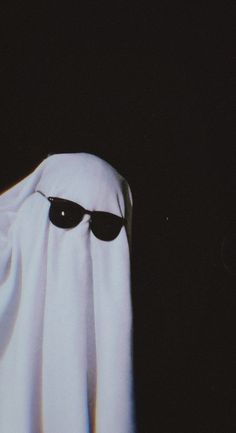 a white ghost with black sunglasses on it's face and eyes covered by a white cloth