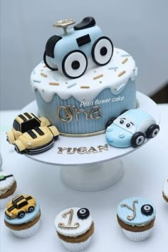 a birthday cake with cars and cupcakes on the top is one year old