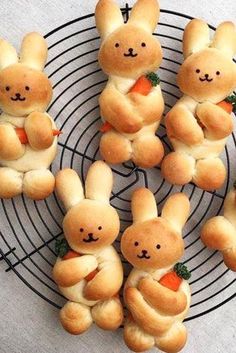 several buns shaped like rabbits holding carrots on a wire rack with other buns in the middle