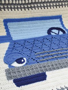 a crocheted blanket with an image of a blue car on it's side