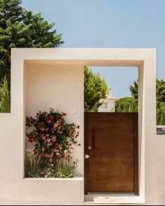 an open door to a white building with flowers growing out of it