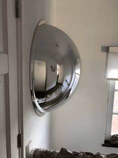 a mirror hanging from the side of a wall next to a bed in a room