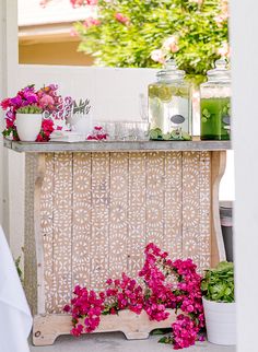 a table with flowers on it in front of a mirror and vases filled with pink flowers