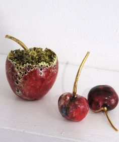 two cherries sitting next to each other on top of a white surface with holes in them