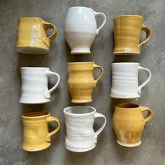 nine yellow and white coffee mugs lined up in a row on the floor,