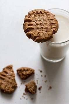 a cookie is being held over a glass of milk