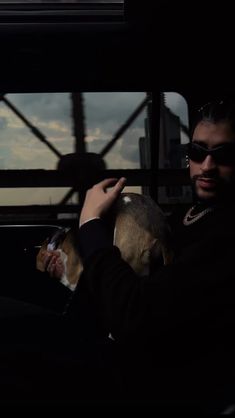 a man holding a dog in his arms while sitting on a bus at night time