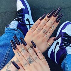 a woman's hands with black nails and tattoos