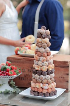 a tower of donuts sitting on top of a white plate next to a bowl of strawberries