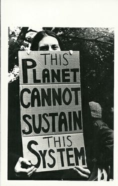 two people holding signs that read this planet cannot not suttain this system