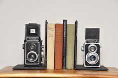 two old fashioned cameras sitting on top of books