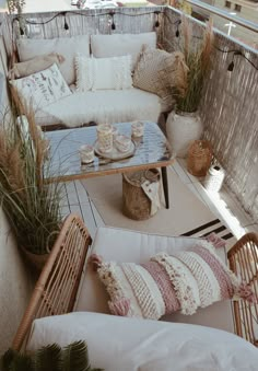 an outdoor patio with wicker furniture and pillows on the couches, coffee table and potted plants