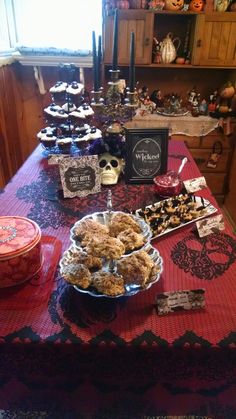 a table topped with lots of desserts on top of a red cloth covered table