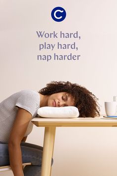 a woman is sleeping on a table with her head resting on a pillow that says work hard, play hard, nap harder