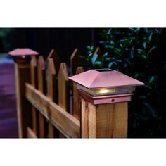 a wooden fence with two pink lights on it's top and one light in the middle