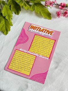 a pink brochure sitting on top of a table next to flowers and leaves