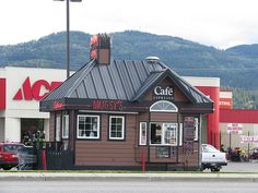 an outside view of a restaurant with mountains in the backgrouds and cars parked on the street