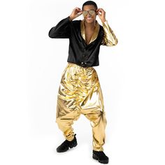 a man wearing gold pants and a black shirt is posing for the camera with his hands on his head