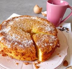 a cake sitting on top of a white plate next to a pink cup